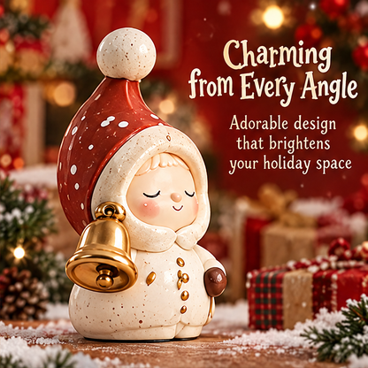 Angled view of the Christmas figurine showing its gold-tone bell, closed eyes, red dotted hat and cream outfit.