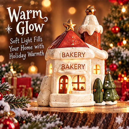 Side and rear-angle view of the Christmas bakery house showing glowing windows, snowy roof trim and gold-tone star toppers.
